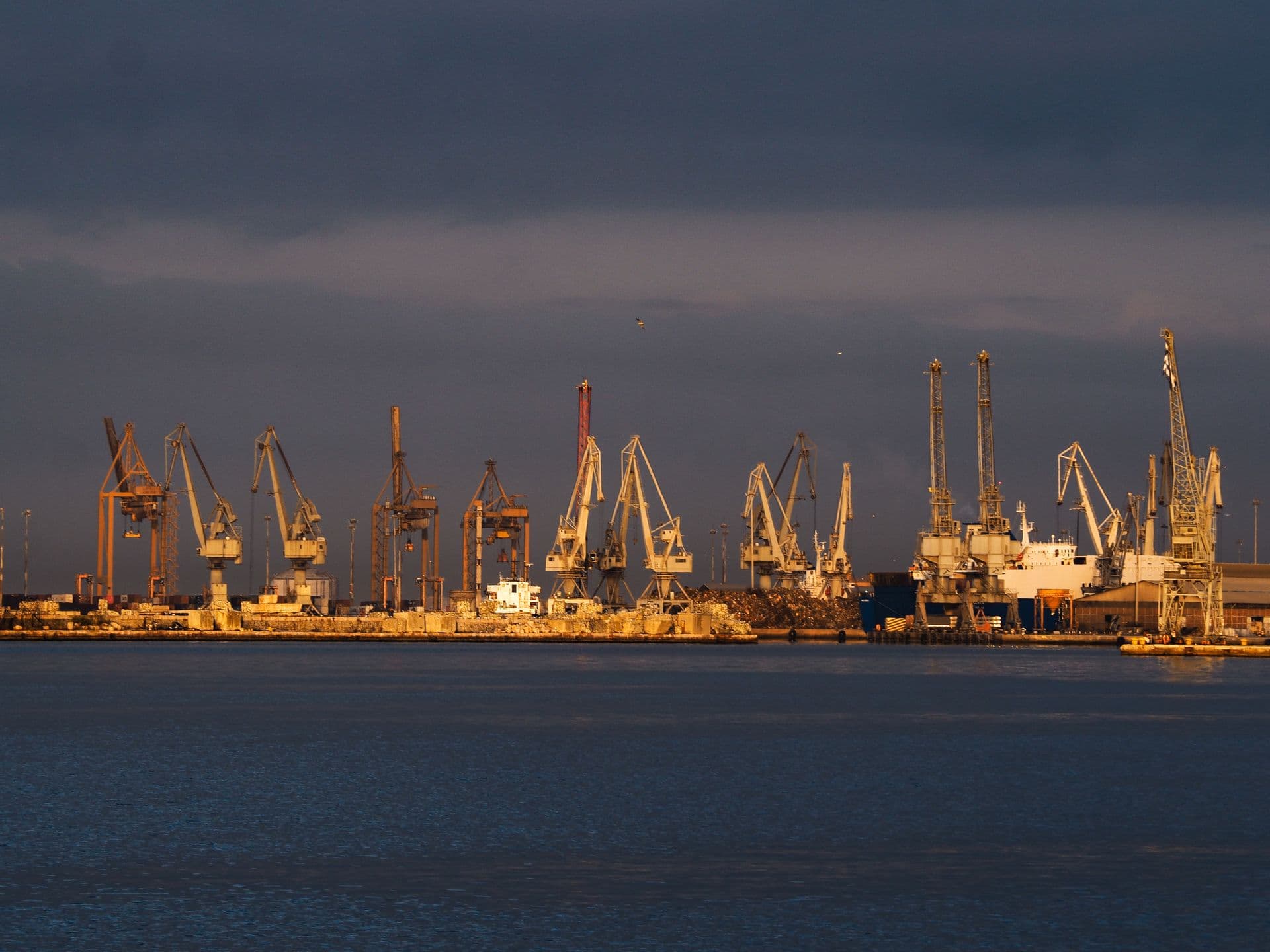 Port cranes lit at sunset
